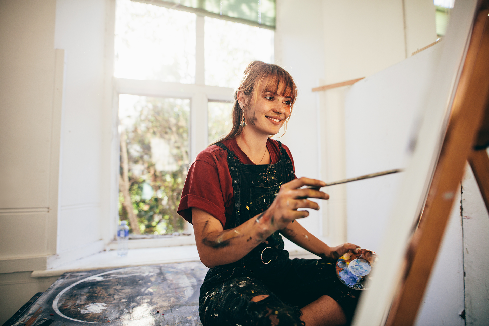 Kvinde der hyggger sig med at male på lærred