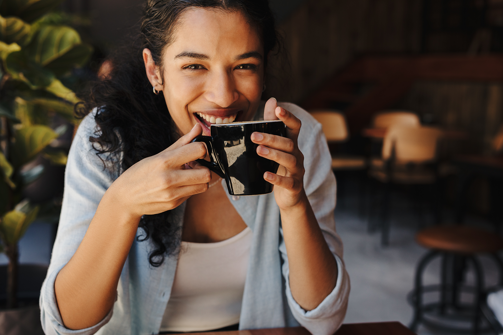 Dame sidder med kaffekop og smiler