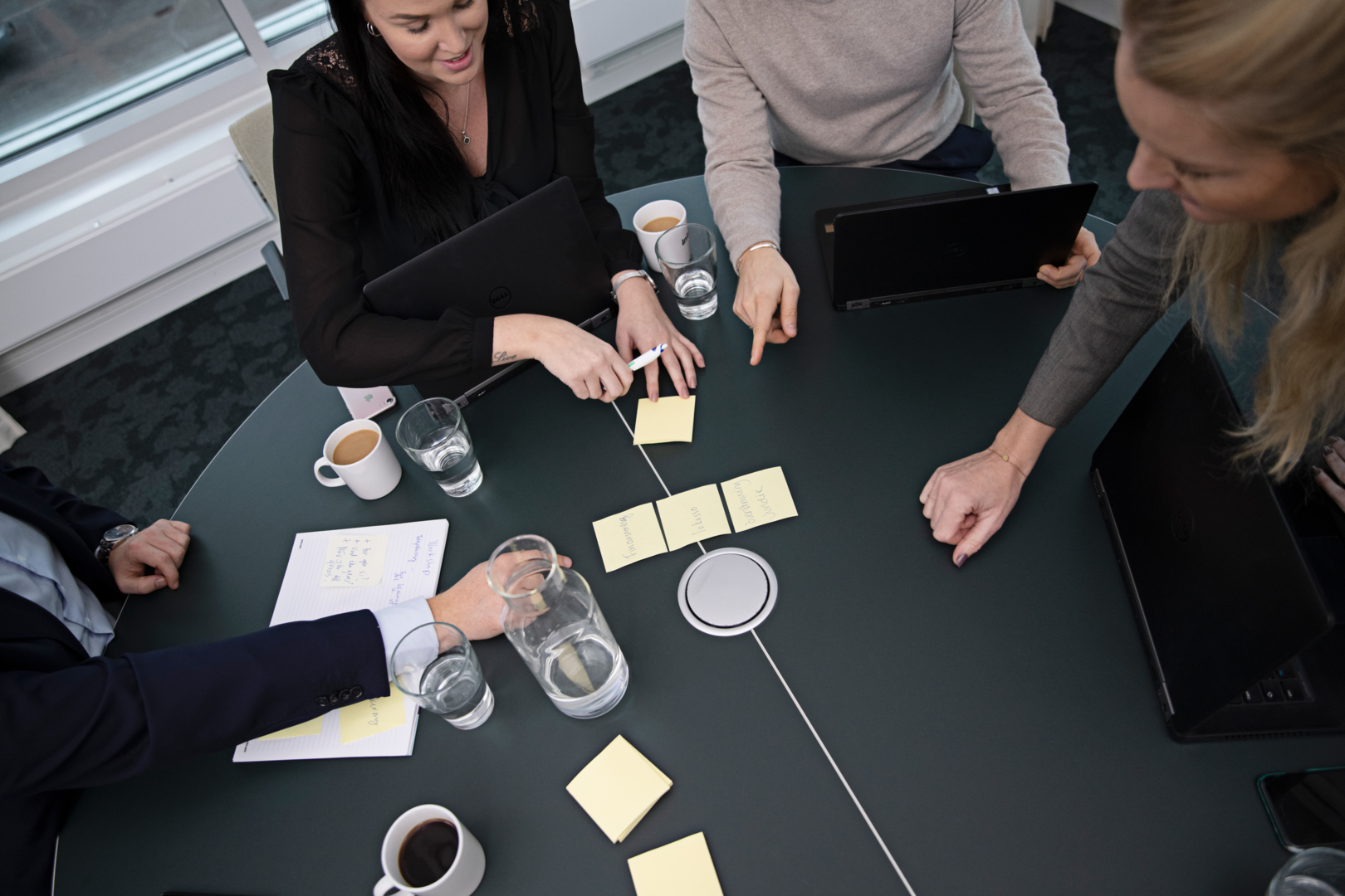 En gruppe forretningsfolk, samlet om et mødebord, diskuterer og samarbejder om udviklingen af en stærk kreditstyringsstrategi for at tilpasse sig usikre økonomiske forhold.